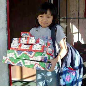 Little girl holding gifts from Santa, Christmas charity donations.