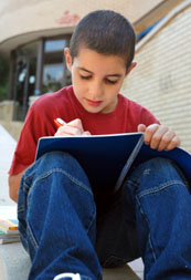 Boy writes a letter to Santa while sitting outside.