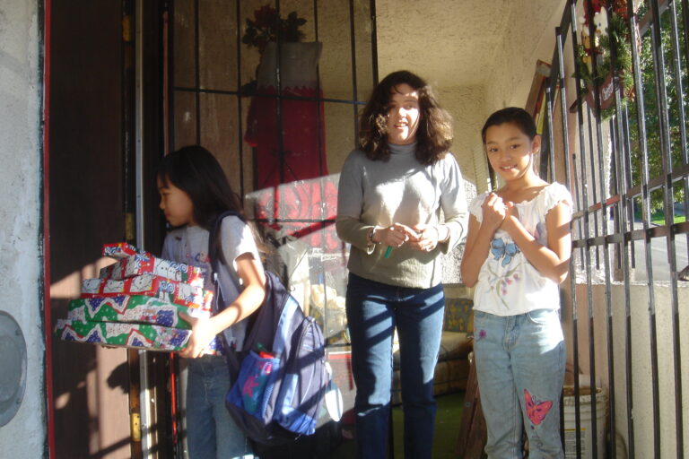 Little girl takes Christmas presents inside her house.