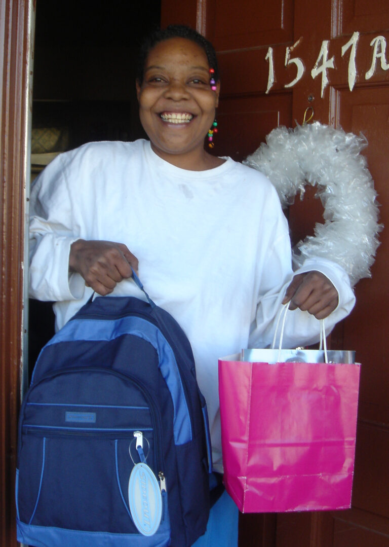 Happy mother holding Christmas gifts at front door.